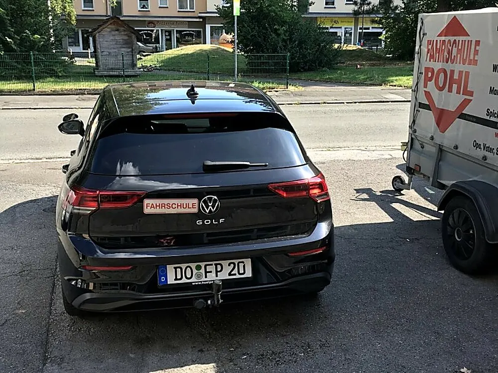 Schwarzer VW Golf der Fahrschule Pohl von hinten, daneben der Anhänger mit der bedruckten Plane, Kennzeichen DO-FP 20